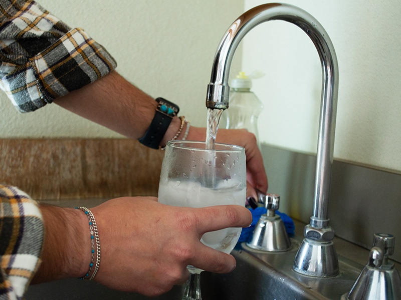 2023-water-reuse-project.jpg Hands holding a drinking glass under a water faucet.