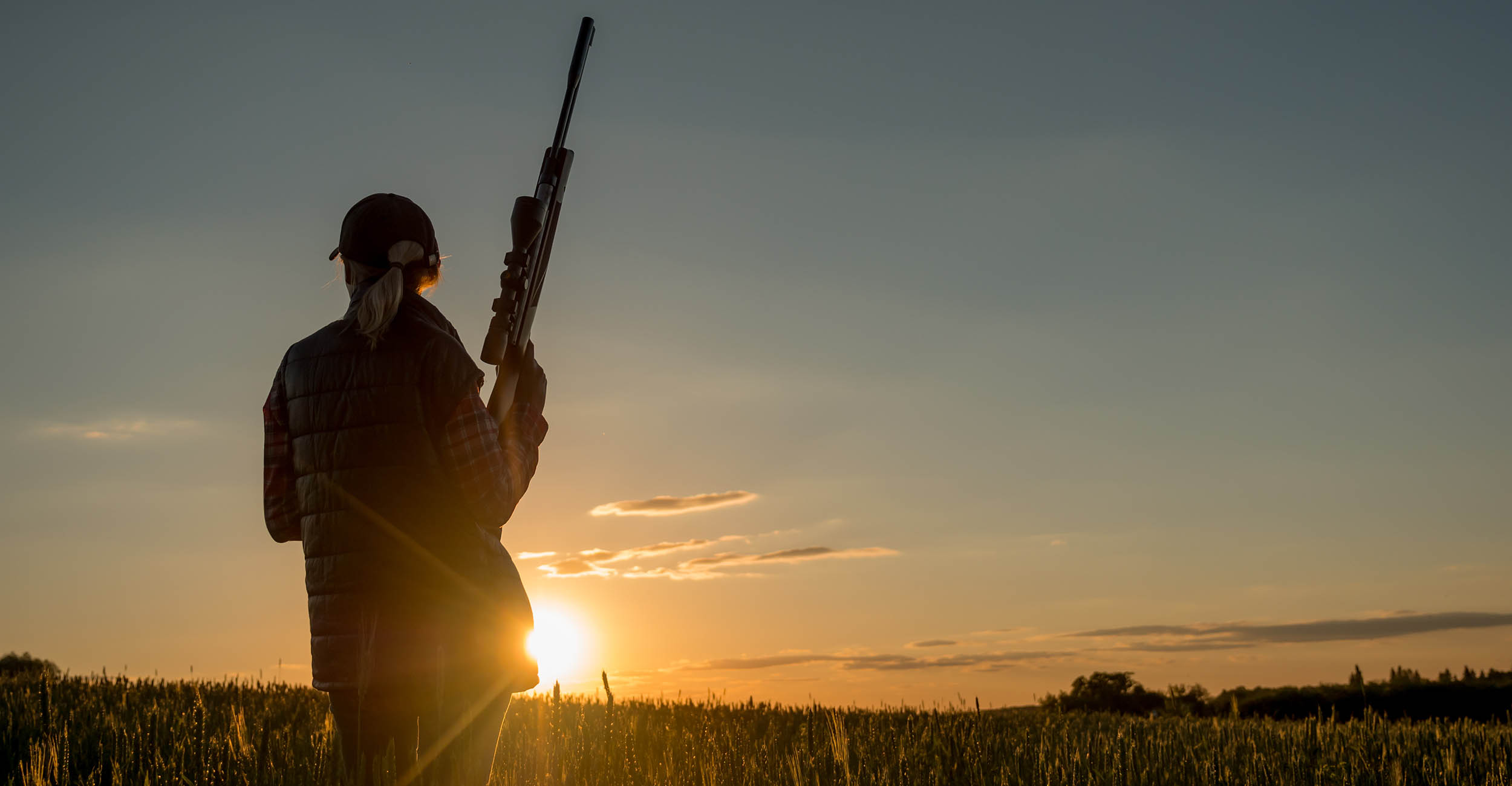 2024-womenhunters-banner.jpg Silhouette of a woman standing outdoors with a shotgun.