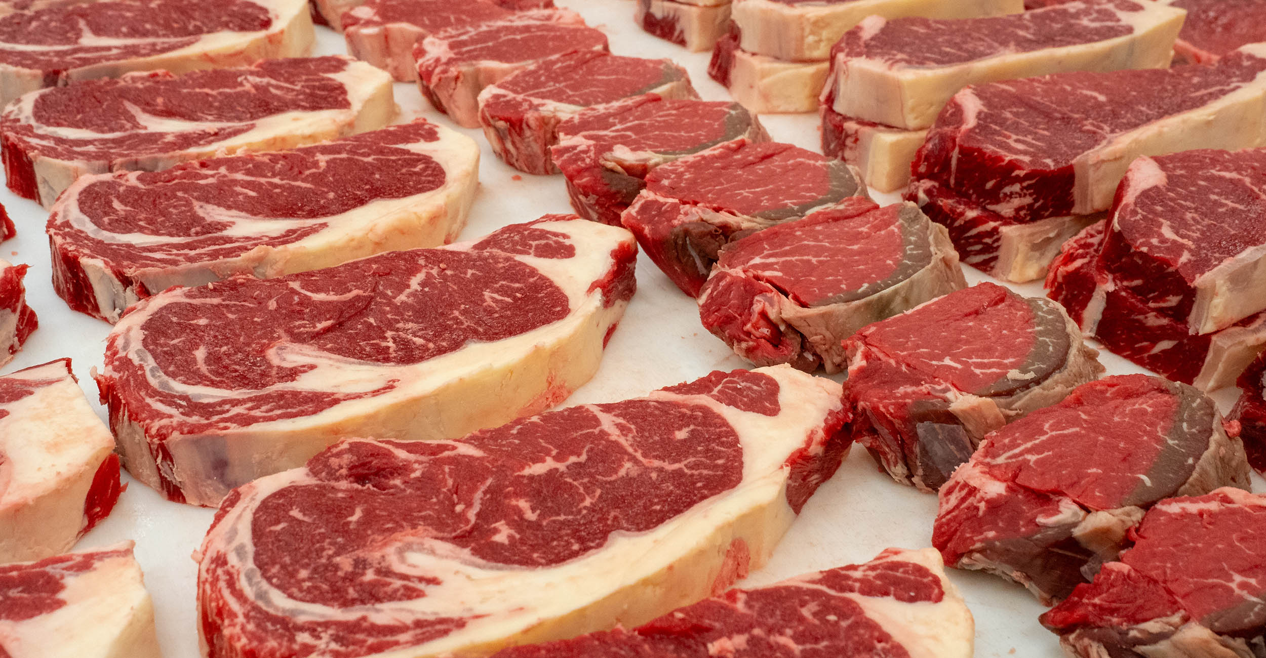 Raw steaks lined up on a counter
