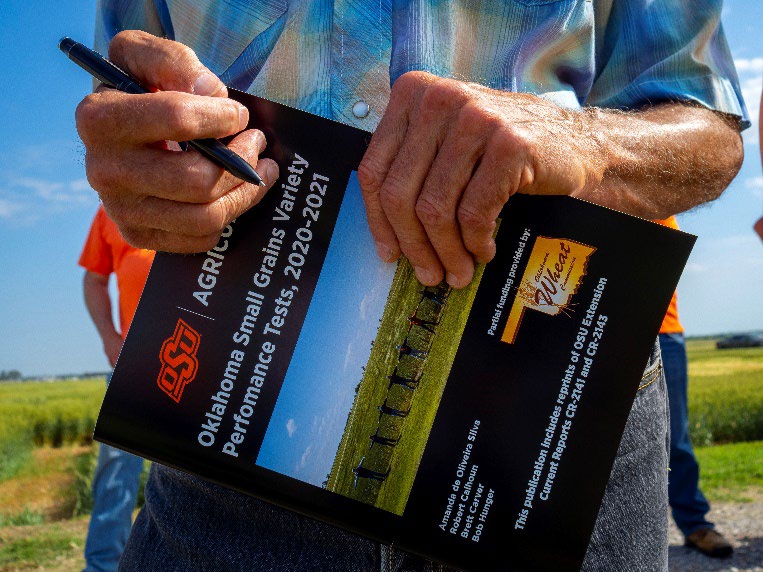 Hands holding an OSU Agriculture Oklahoma Small Grains Variety Performance Tests, 2020-2021 book.